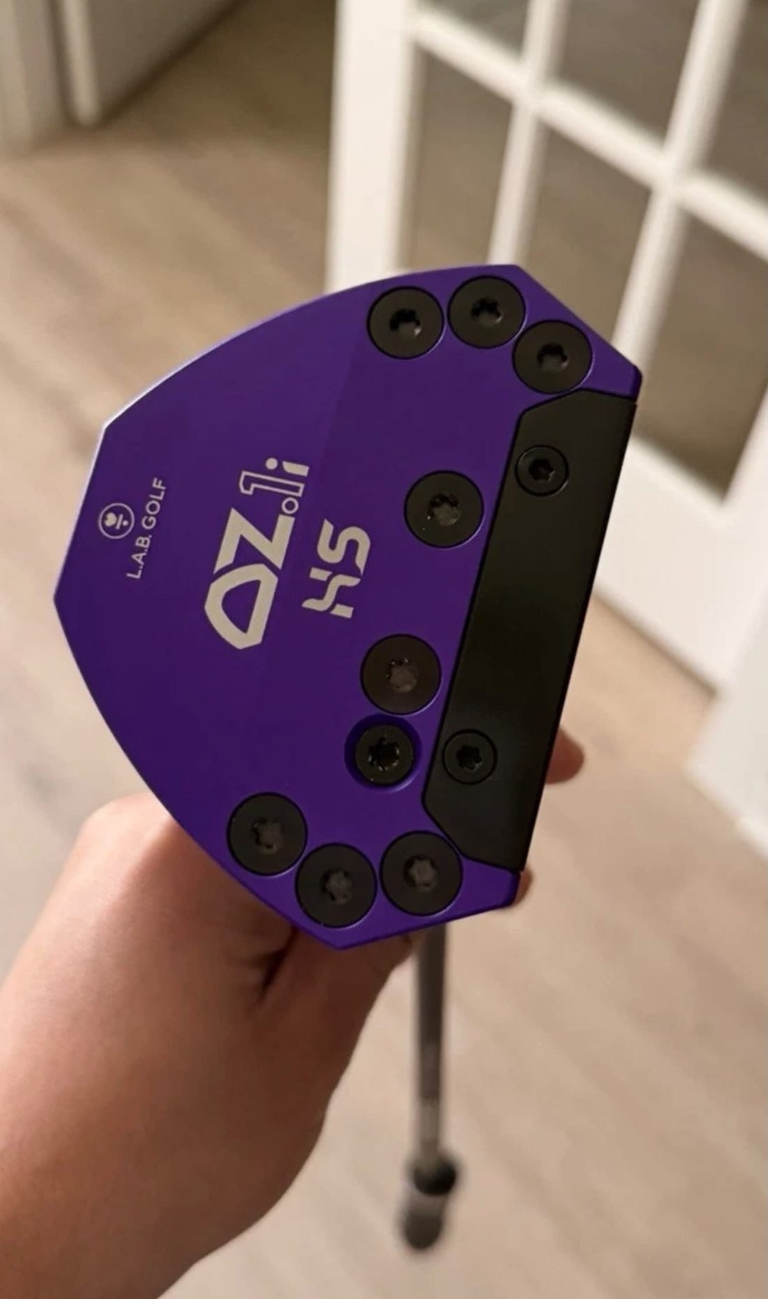 Sole of the custom purple L.A.B. OZ.1i HS putter showing the adjustable weight ports and L.A.B. Golf branding